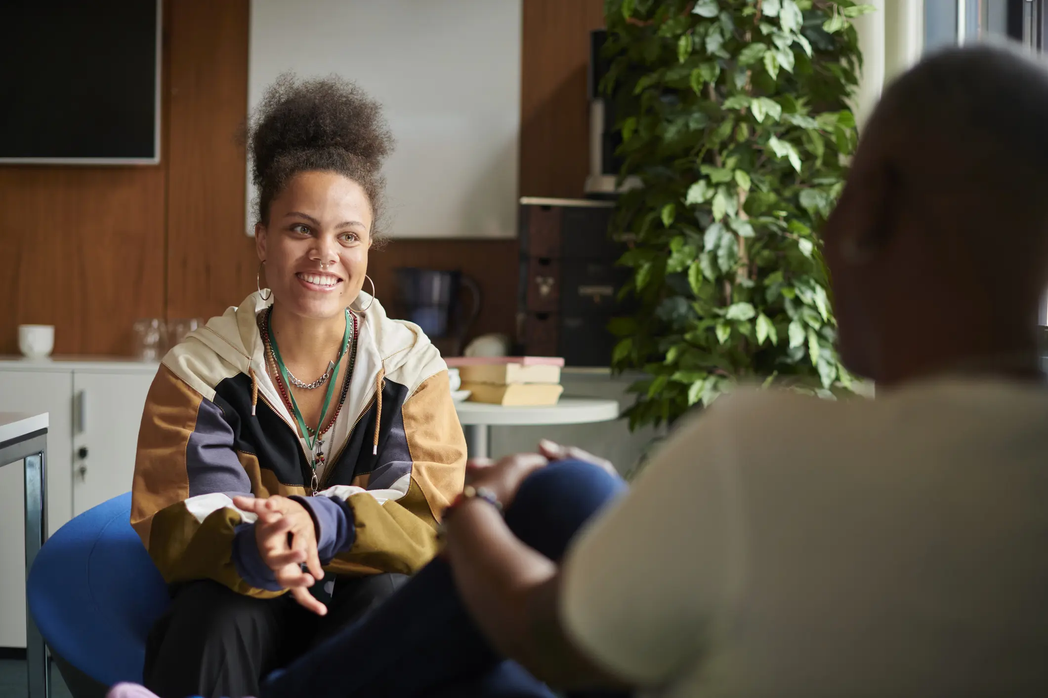 Young African-American female teenager having positive conversation with therapist on couch
